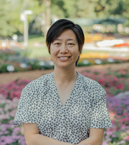 Portrait of an asian woman with a short hair cut in front of flower beds