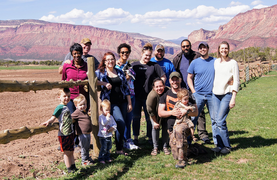 A large family standing at the edge of a fence with a mountain backdrop