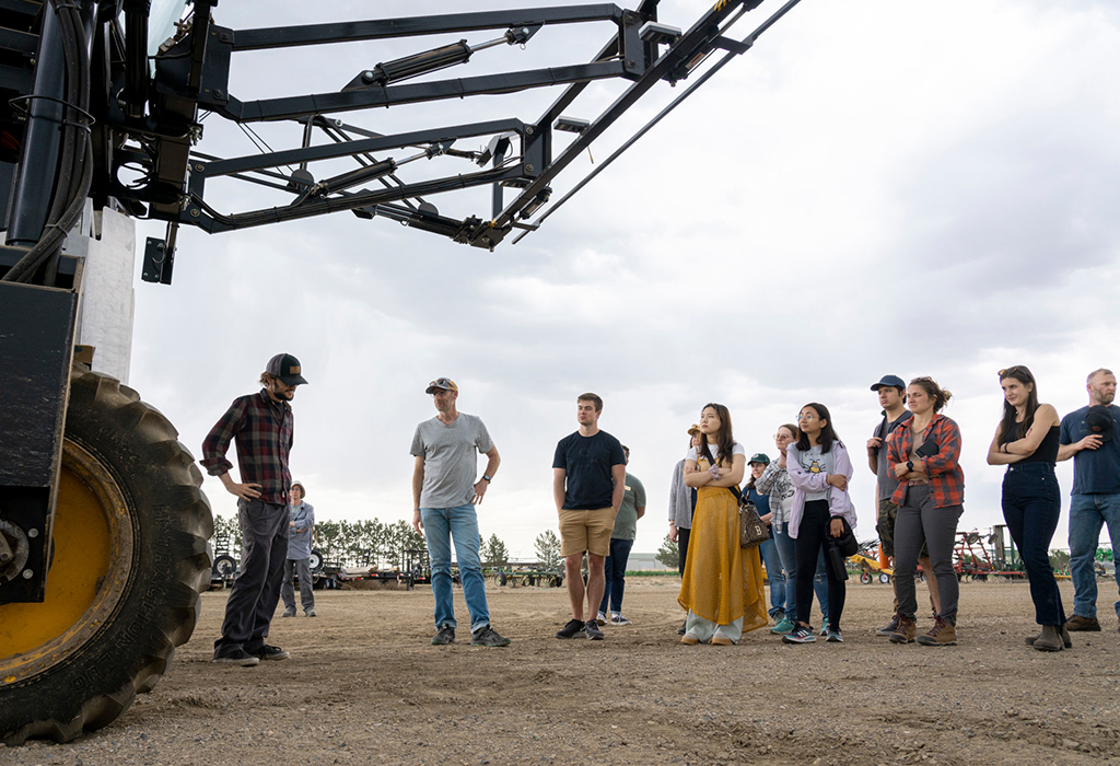 group looks up at large piece of farm machinery