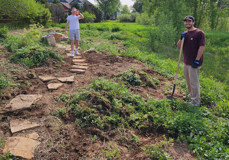Students build a stone path through garden.